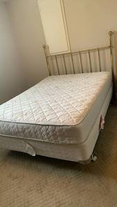 lot 928 image: Full size Bed with Mattress and Box Spring  with brass headboard located in basement
