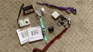 lot 1726 image: Polaroid digital camera, apple. Charger, step counter, thumb drive, headsets and alarm clock