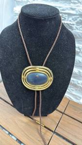 lot 93 image: Oval Leather Bolo Tie with Braided Cord and Gold-Tone Frame