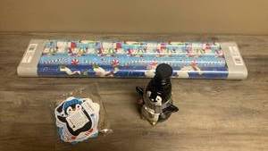 lot 544 image: Holiday Wrapping Paper Roll 4-Pack, Penguin Soap Dispenser and penguin name tags with rope ties.