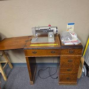 lot 44 image: Vintage Montgomery Ward Signature Cast Metal Sewing Machine Model URR 285 and sewing table w drawers - includes some bobbins, feet, templates and manual. (top of machine not closing properly - but sews great)