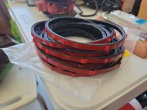 lot 45 image: Adhesive-Backed Rubber Seal Strip with Red Tape Backing Coiled - Retail $0