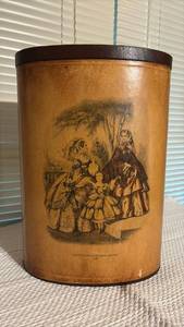 lot 3016 image: Vintage waste bin features a classic print of Godeys Americanized Paris Fashions from 1860 set against a warm, distressed tan finish