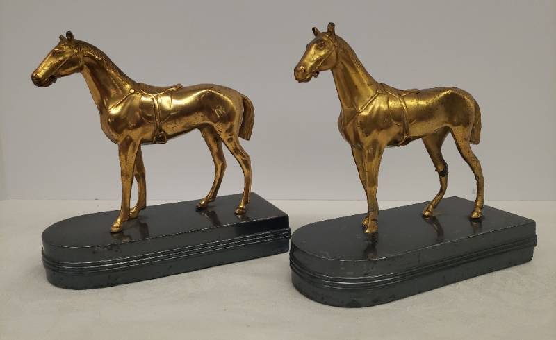 lot 138 image: Antique 1920s-1930s Gold Metal Horses with Riding Gear - Bookends on Metal Weighted Bases - one has Hoof damage - 6in L x 6in T x 2.5in W