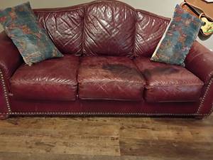 lot 919 image: Leather Trend Couch with Brass Brads. With 2 Throw Pillows. Has 2 discolored seat cushions.  35 x 89 x 24.