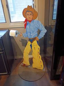 lot 932 image: 4ft tall Metal Cut Out of Elvis as a Cowboy Holding Toilet Paper.  Diameter 2ft.
