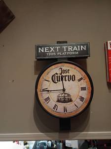 lot 944 image: Jose Quervo Clock with Next Train This Platform.  Approximately 30in tall.  Will need to bring ladder to get off wall.  Comes with extra face for the back side