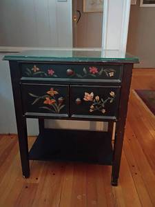 lot 965 image: Black Wooden Cabinet with Painted Floral Design.   Glass Top with Drawer and Storage   28 x 24 x 16