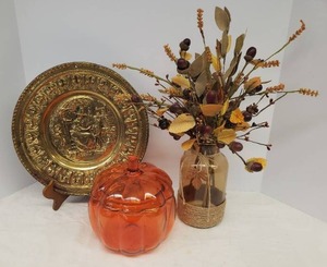 lot 65 image: Vintage Embossed Brass Wall Plaque 12in W, Fall Floral Arrangement in Amber Glass Vase 18in T, and Glass Pumpkin CookieCandy Jar - 7in W x 8in T