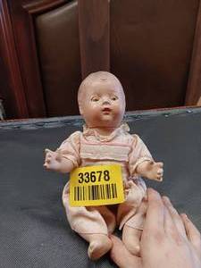 lot 33678 image: Antique baby doll with a compositionbisque head and a soft cloth body,