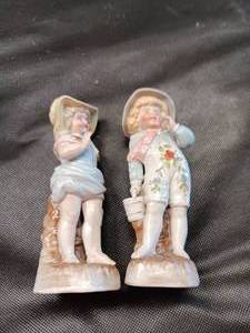 lot 33679 image: Pair of vintage hand-painted bisque porcelain figurines, a young boy and girl in pastel outfits and hats