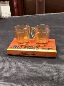 lot 33669 image: Vintage amber glass mini beer mug shot glasses Big Shot souvenir mugs, resting on a small wooden stand