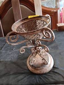 lot 33786 image: Ornate metallic pedestal bowl featuring intricate scrollwork and a rounded base.