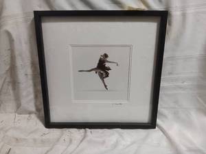 lot 33863 image: Framed black-and-white art print of a graceful ballerina performing a leap pose, set inside a white mat and a dark wood frame