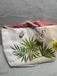 lot 33903 image: Cream-colored canvas beach tote bag featuring a green palm leaf print and braided rope handles