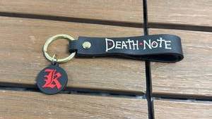 lot 29 image: Death Note Keychain with Black Strap and Red Symbol Charm