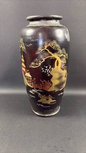 lot 75 image: Aluminum Painted Dark Ground Vase with Gold and Red Decorative Landscape Stencil Design Vase 12 inches tall approximately 6 inches diameter at widest point