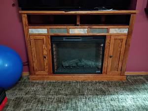 lot 903 image: Oak Electric Freestanding Fireplace.  Glass Front with Faux Logs, Side Storage and Remote.  38 x 56 x 21.  Located in basement
