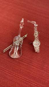 lot 1042 image: Swarovski crystal saxophone  and violin figurine featuring a clear faceted body and silver-toned metal accents