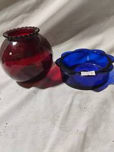 lot 34750 image: Vintage Anchor Hocking Royal Ruby red glass rose bowl with a ruffled top alongside a vibrant blue scalloped glass dish