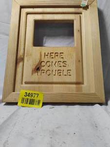 lot 34977 image: Light wood decorative concealment frame with the carved text Here Comes Trouble.