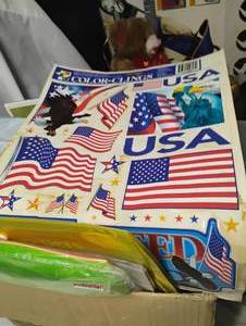 lot 35018 image: USA window clings, 12x12 paper organizer, assorted colors open stock paper, 12 pack of christmas iron-on clothing patches, among other things