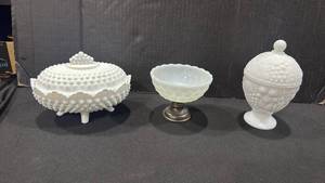 lot 1006 image: Hobnail milk glass oval covered candy dish with three feet, Avon milk glass covered jar and other pedestal dish