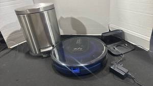 lot 1244 image: Eufy RoboVac Robot Vacuum Cleaner with Charging Dock and small step trash can 12 inches tall