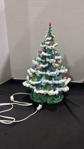 lot 1252 image: Green ceramic Christmas tree featuring white snow flocking and bright multicolored plastic bulb lights 17 inches tall small breakage in flocking