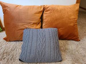 lot 7122 image: 2 squishy coppertone throw pillows and one cable knit throw pillow.