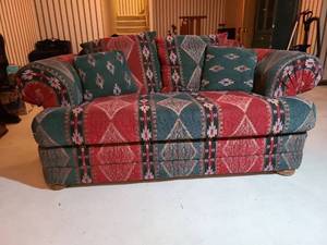 lot 2033 image: Upholstered loveseat with geometric pattern pillows and rolled arms, 28in tall, 74in wide, 38in deep, pet scratches on back of loveseat.