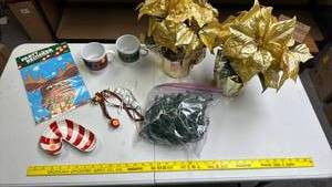lot 250 image: Two gold tone faux Poinsettia plants, mugs, candy cane ceramic plate, Pin the Nose on the Reindeer, bag of tree lights, and some bells on string