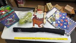 lot 253 image: Christmas Holiday Decorations - metal Santa with List wall art, green ornaments, gift bag and boxes assortment, door draft stopper with snowflake