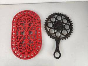 lot 399 image: 2 Decorative Cast Iron Trivets Red Oval and Dark Handle Gear Design