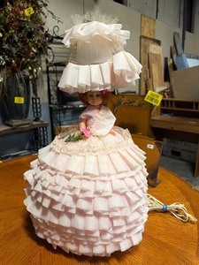lot 35208 image: Vintage doll mounted inside a decorative bedside lamp with a ruffled lampshade.