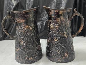 lot 1009 image: Pair of Decorative Metal Pitchers with Embossed Floral and Geometric Design - Retail $0