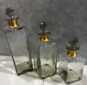 lot 1068 image: 3-Piece Glass Decanter Set with Faceted Stoppers and Brass Collars Tallest is 12 inches