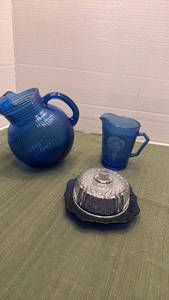 lot 1107 image: Hazel Atlas Shirley Temple Cobalt Blue Glass Pitcher, ribbed tilt pitcher and Imperial cobalt blue butter or cheese dish with glass lid