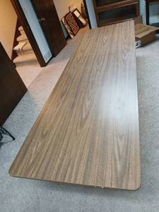 lot 2209 image: Folding Table Wood Grain Top Metal Frame 23in x8ft  x 30 inches with homemade table skirt  located in basement