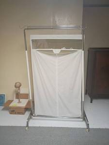 lot 988 image: 2 Clothing Racks.  One with zip up cover is 63 x 36 x 20.  Located in basement