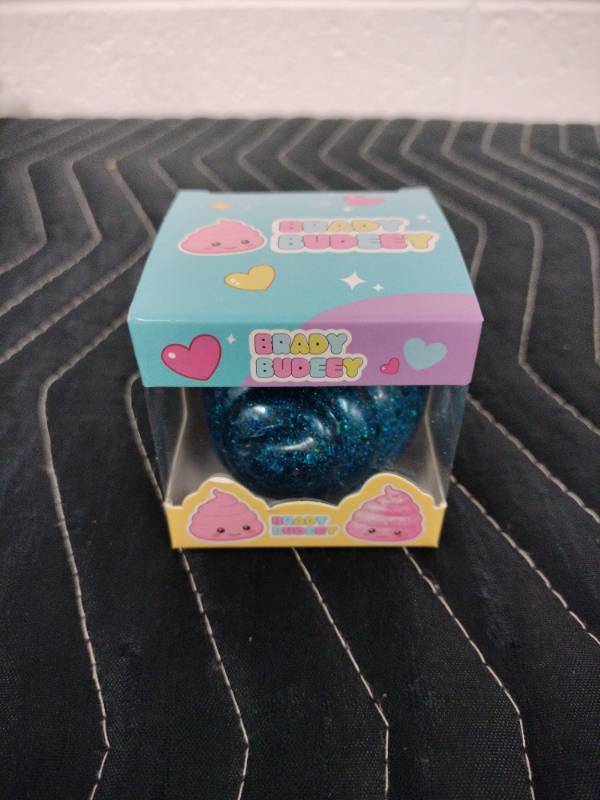 lot 142 image: Brady Budeey Blue Glitter Poop Emoji Squishy Toy in Display Box