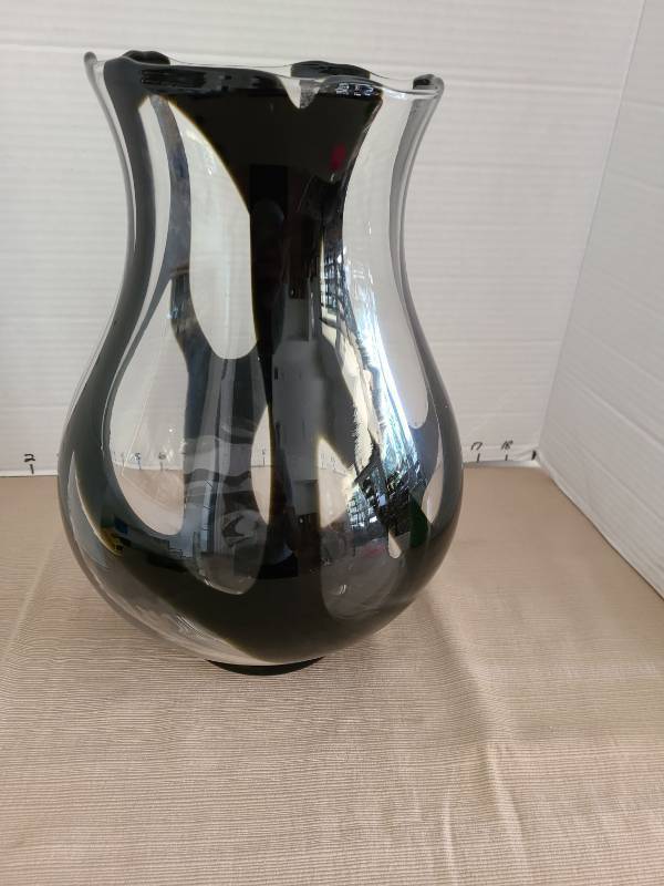 lot 1009 image: Handmade blown swirled glass black and clear vasecandle holder with wavy top rim, 12in tall