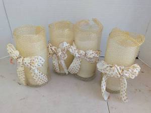 lot 4219 image: Set of 4 Cream battery operated Pillar Candles in Glass Holders with Gold Mesh Wrap and Dotted Bows