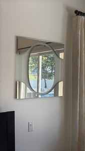lot 20 image: Wall mirror with a curved, wave-shaped Wall mirror with a curved, wave-shaped Wall mirror with oval band across the center of the panel. 30 x 30