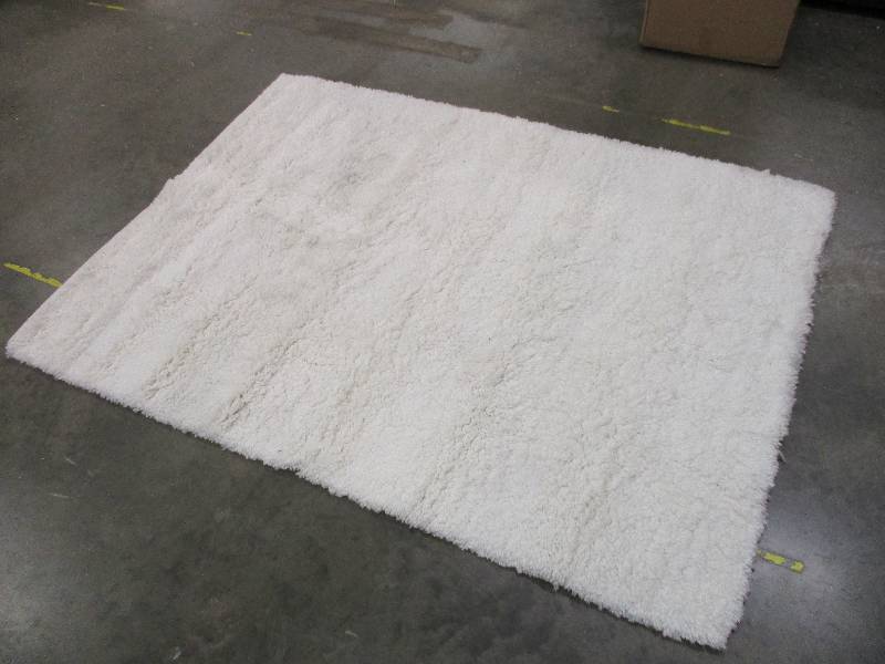 lot 148 image: 4ft x 56 White shag area rug has some dirt from the warehouse