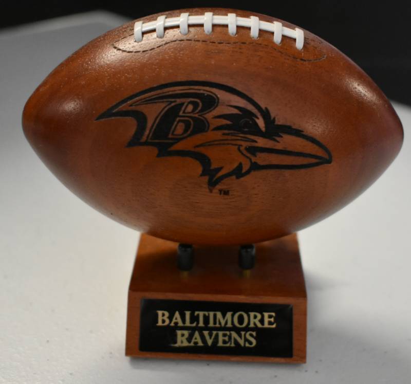 lot 1096 image: Baltimore Ravens National Football League Wooden Team Logo Football With Stand - 5 Inches Wide - With Metal Team Name Plaque