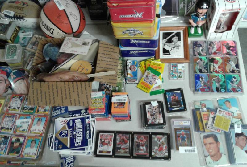 lot 1500 image: Table Full of Sports Memorabilia Including Vintage Cards, Autographs, Basketball, Football, Lunchboxes, Table of No-Bid Items from Six Months of Auctions