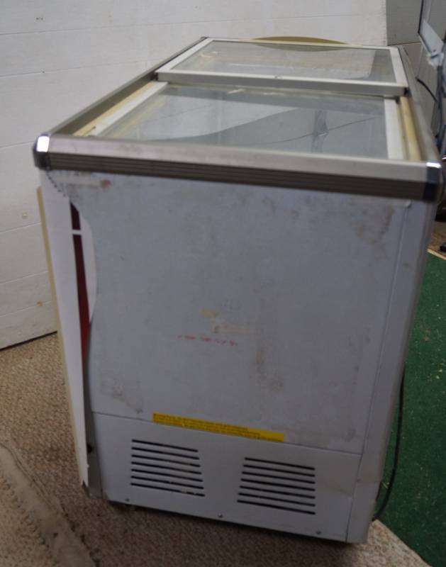 lot 1494 image: Hussmann Clear Top-Opening RefrigeratorFreezer- Powers on and gets cold-Has frame for advertising poster-One top panel needs slight repair-See video for details-standard household plug