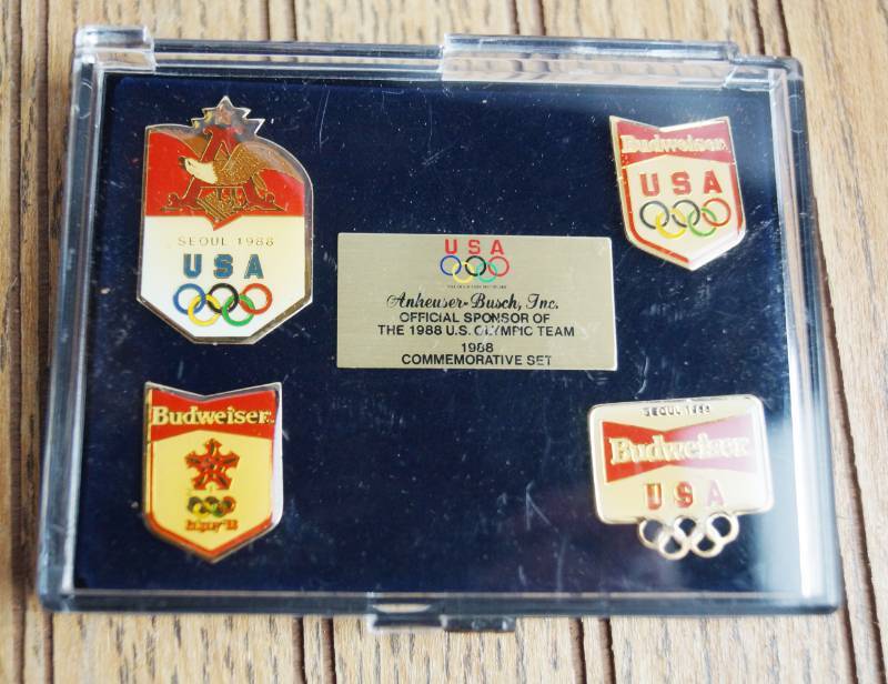 lot 1656 image: Lot of 4 Olympic Budweiser Enamel Commemorative Pins - In case - Official Sponsor 1988 Olympics
