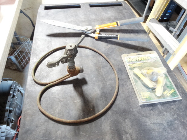lot 6482 image: Lot with weed trimmer cutting head, fiskars 23 hedge shears and sprinkler.